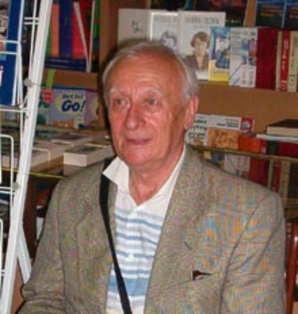 Artistul plastic Radu Bercea lângă standul cu carte românească Artistul plastic Radu Bercea lângă standul cu carte românească