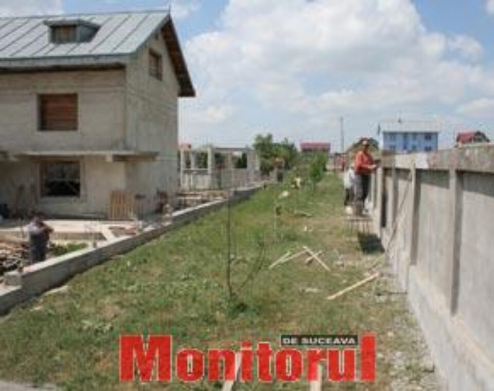 Oamenii se uită cu jind la drumul de acces de peste gard