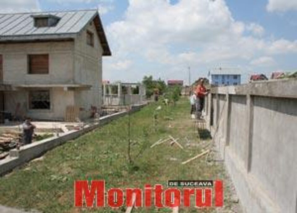 Oamenii se uita cu jind la drumul de acces peste gard