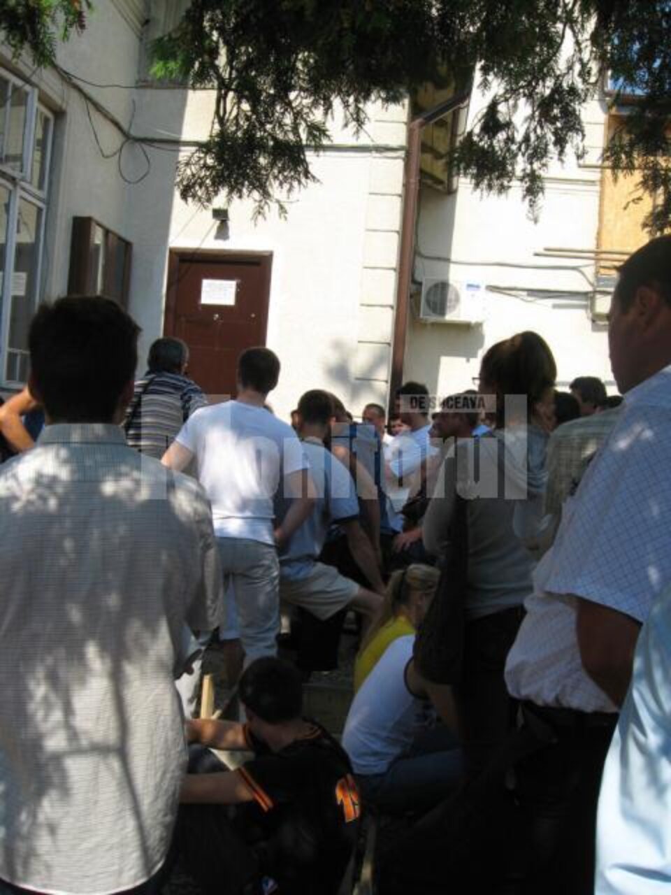 Oamenii așteaptă în aer liber să le vină rândul la ghișeu