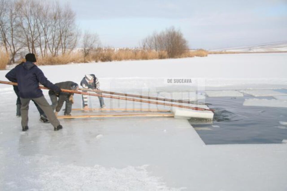 Sătenii scot din iaz blocuri de gheață din care fac crucile