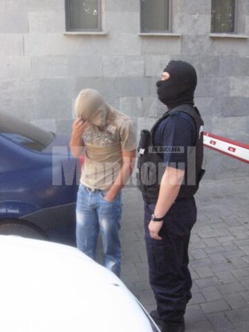 Unul dintre suspecți, escortat de un cagulist