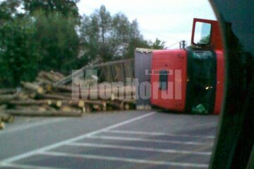 Tir încărcat cu bușteni, răsturnat în drum
