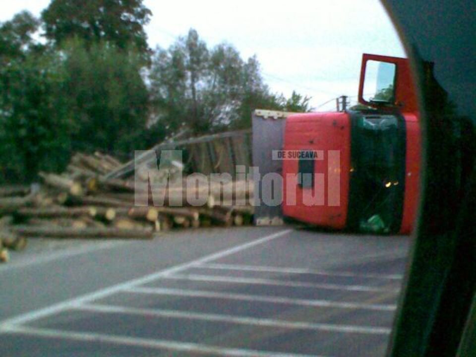 Tir încărcat cu bușteni, răsturnat în drum