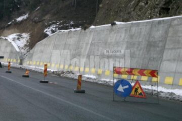 De deasupra zidului de beton ridicat pentru consolidarea dealului de lângă șosea au început să alunece pământ și pietriș