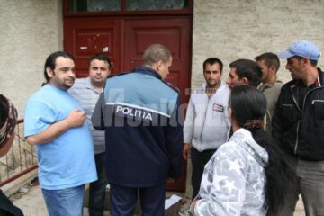Secretarul, consilierul juridic, polițistul din sat și romii nemulțumiți, în fața sediului unde sunt depozitate ajutoarele