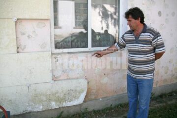 Directorul Școlii Rotunda, Liviu Petrică Grigore, arătând spre fațada scolii