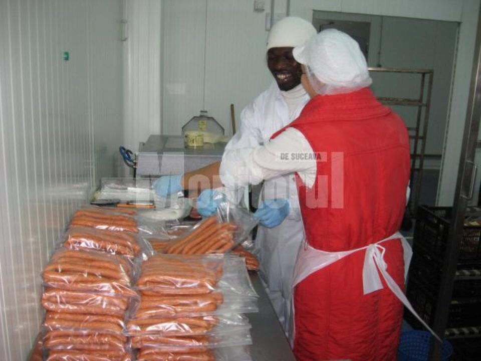 James Okere Gospel lucrează la mașina de ambalat, în echipă cu sora lui Alexandru Scheul, Ancuța