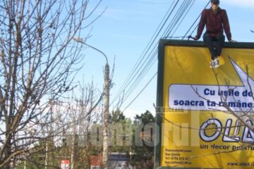 Panoul publicitar a atras atenția trecătorilor, surprinși de imaginea tânărului cocoțat