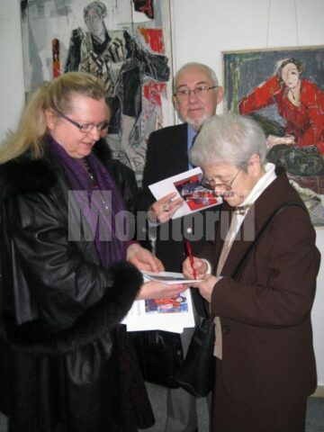 Alma Redlinger oferindu-i un autograf - pe catalogul expoziției - artistei plastice Lucia Pușcașu
