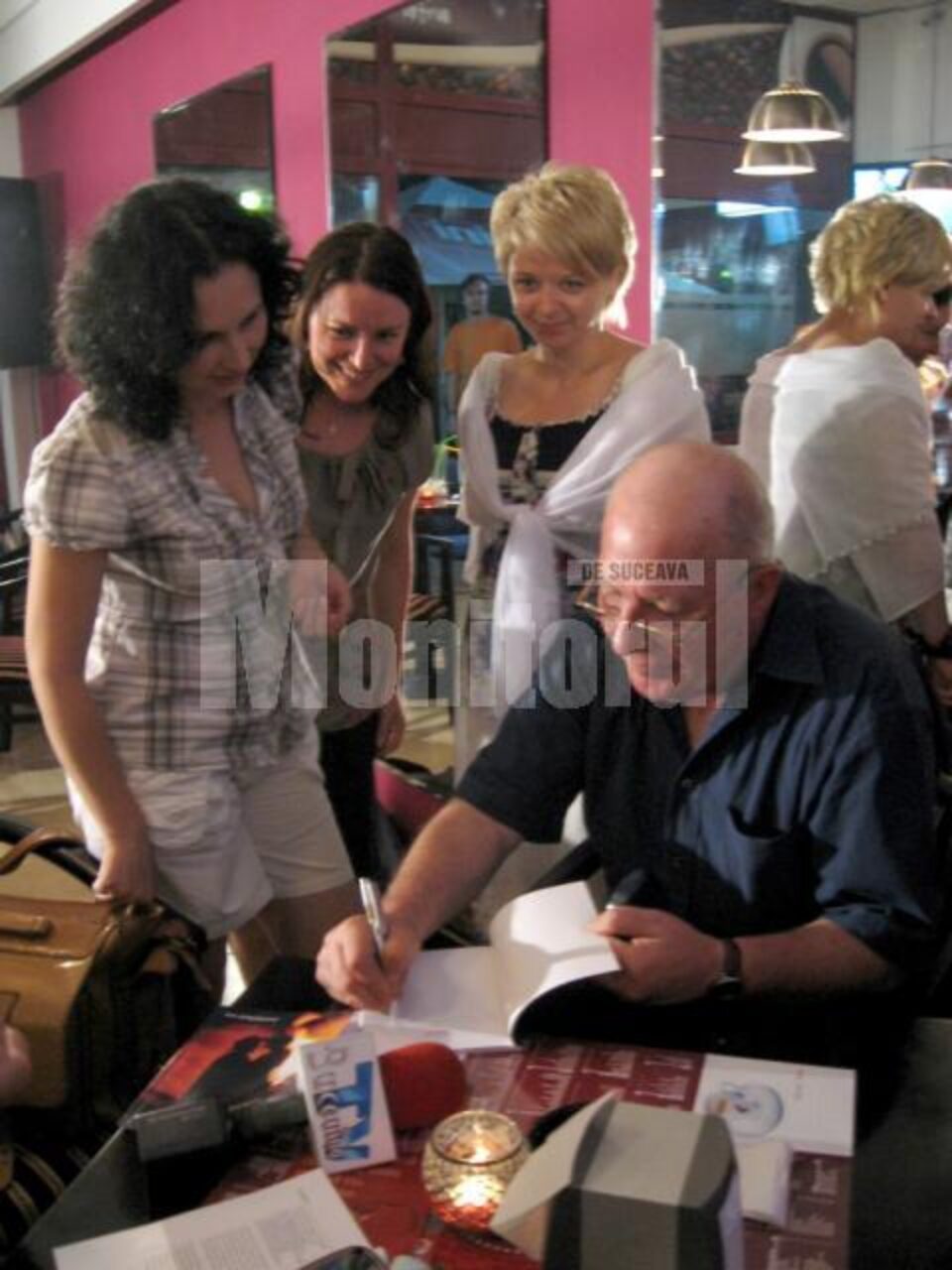 Ion Drăgușanul oferind cărți cu autograf cititorilor