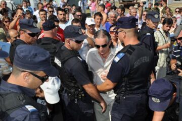Miron Cozma, ținut de jandarmi, în timpul manifestărilor prilejuite de Ziua Marinei. Foto: MEDIAFAX