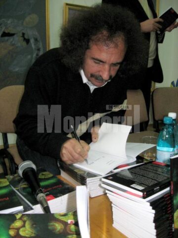Vasile Tudor oferind autografe pe volumul său de debut