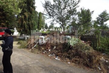 Intrarea în cimitir, străjuită de un morman de gunoi