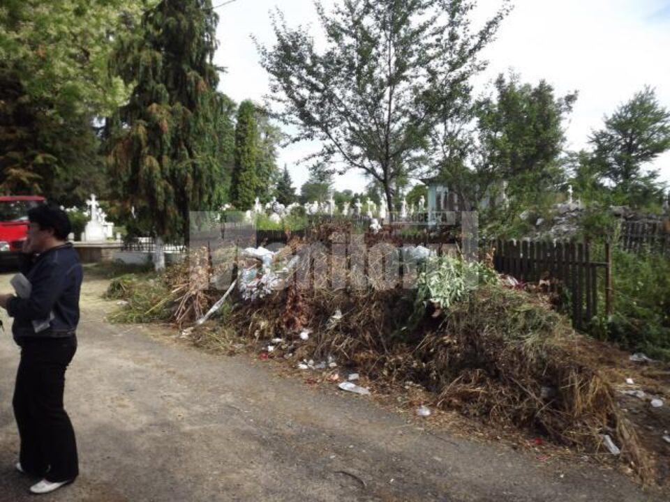 Intrarea în cimitir, străjuită de un morman de gunoi