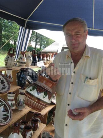 Meșterul popular băimărean Cornel Sitar ținând în mâini un ulcior numit cana mester