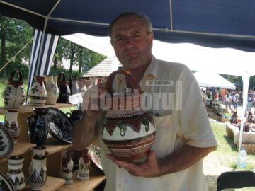 Meșterul popular băimărean Cornel Sitar ținând în mâini un ulcior numit cana mester