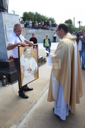 Dan Răican, donând Bisericii din Cacica un tablou pictat de o tânără fără mâini