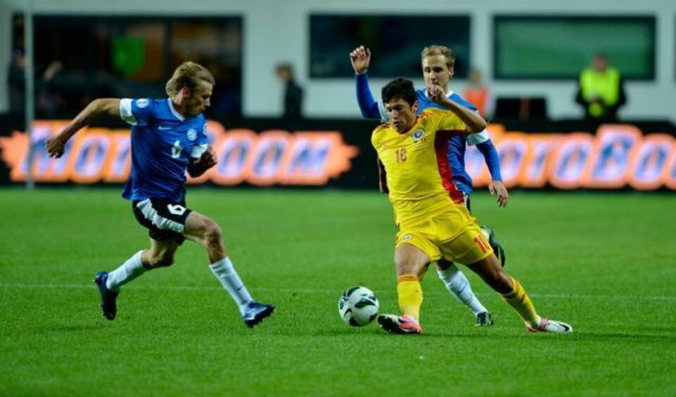 Cristian Tanase (centru), de la echipa reprezentativă a României, se luptă pentru balon cu un jucător de la echipa reprezentativă a Estoniei