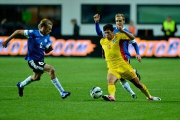 Cristian Tanase (centru), de la echipa reprezentativă a României, se luptă pentru balon cu un jucător de la echipa reprezentativă a Estoniei
