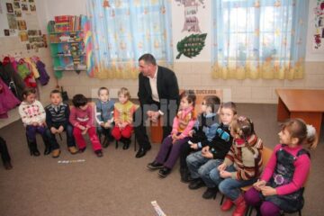 Cu ajutorul educatorului, copiii recită în cor poezii și cântecele