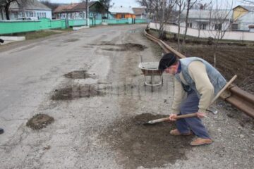 Sătenii s-au transformat în drumari și acoperă gropile cu pământ