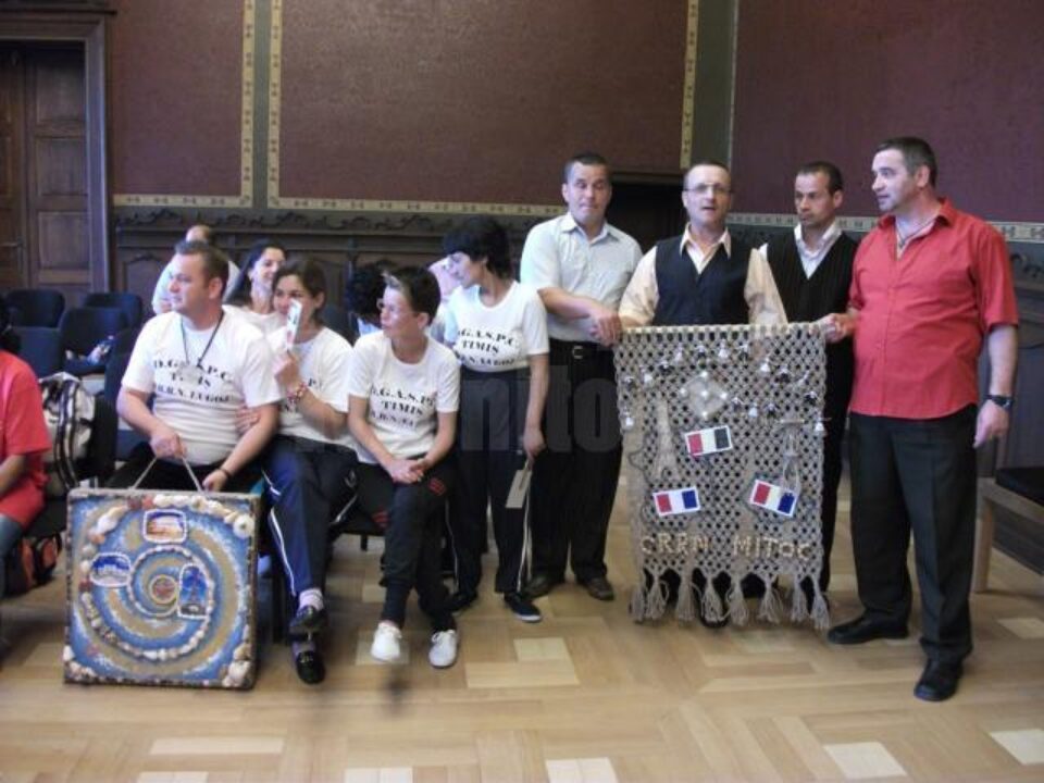 Cei patru asistați ai Centrului de Reabilitare Mitocu Dragomirnei și afișul lucrat manual din sfoară împletită