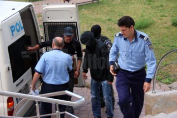 Fostul polițist Olinici (cu gluga pe cap) și Mihai Halip împart aceeași pereche de cătușe