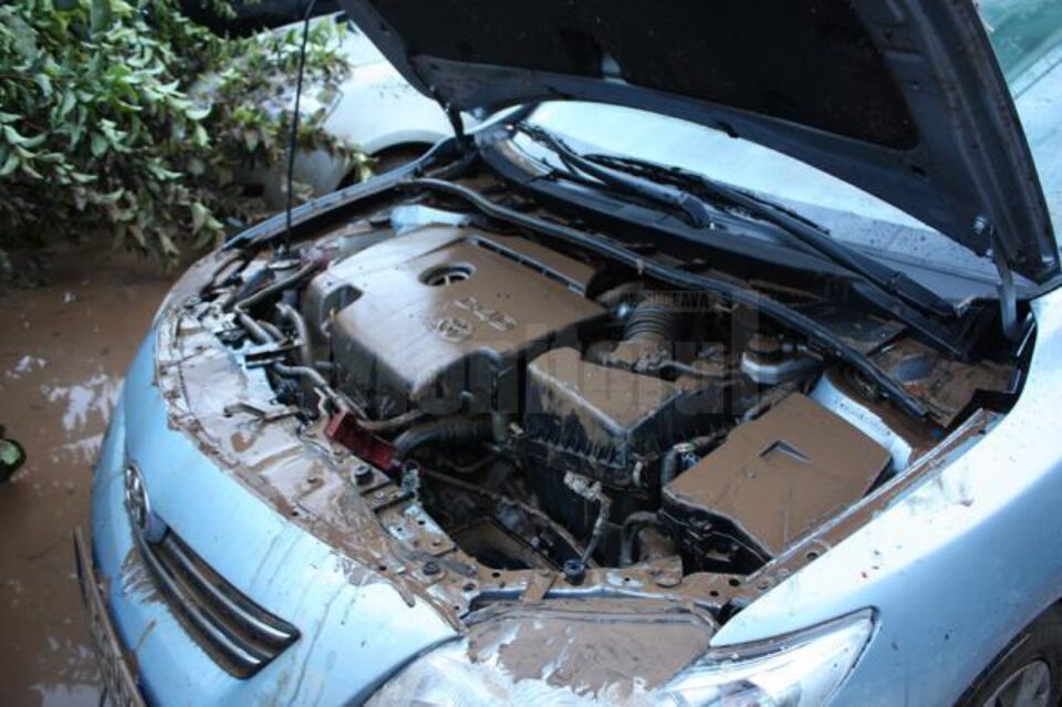 În imagini apar mașini acoperite aproape în întregime de ape, dar și mâlul din interior de după retragerea viiturii