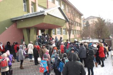 Copiii așteaptă permisiunea de a intra în școală