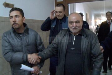 „Norocel” (stânga) și tatăl său, duși de polițiști în sala de judecată, cu câteva minute înainte de a fi arestați preventiv