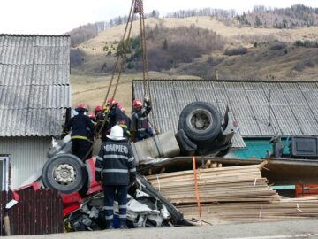 Mașina transformată într-un morman de fiare a fost ridicată cu mare greutate de pompieri, cu ajutorul unei macarale