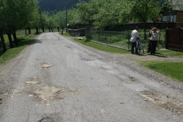 Drum asfaltat cu fonduri europene, reparat în bătaie de joc cu pământ și piatră