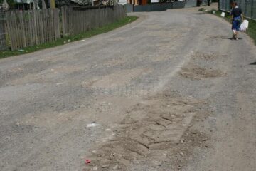 Drum asfaltat cu fonduri europene, reparat în bătaie de joc cu pământ și piatră