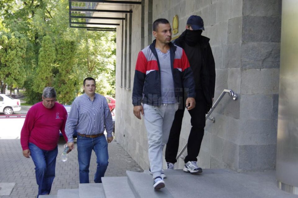 Dragoș Amariței (36 de ani), în față, cu gească roșu cu negru, și Mihai Boroianu (56 de ani), cu bluză roșie, aduși vineri de polițiști la sediul DIICOT Suceava