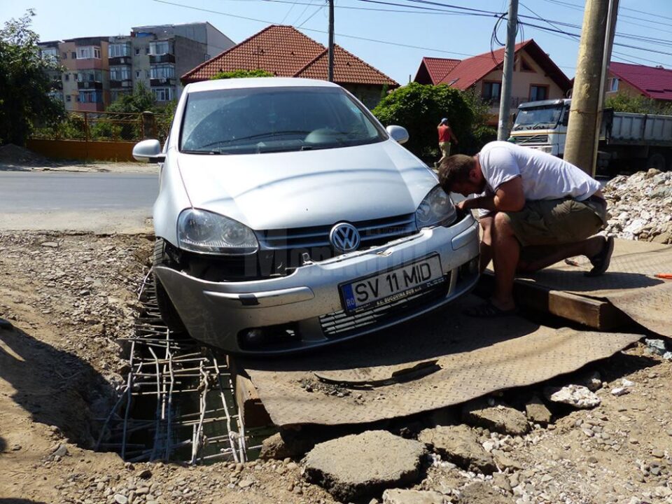 Mașina avariată după ce placa de fier pusă peste zona în care se lucrează a alunecat
