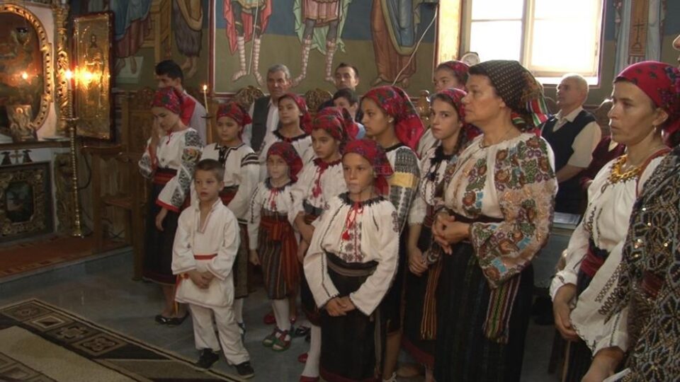 Îmbrăcați în costume naționale, copiii cântă în corul bisericii păstorite de preoții Saftiuc, tată și fiu