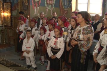 Îmbrăcați în costume naționale, copiii cântă în corul bisericii păstorite de preoții Saftiuc, tată și fiu