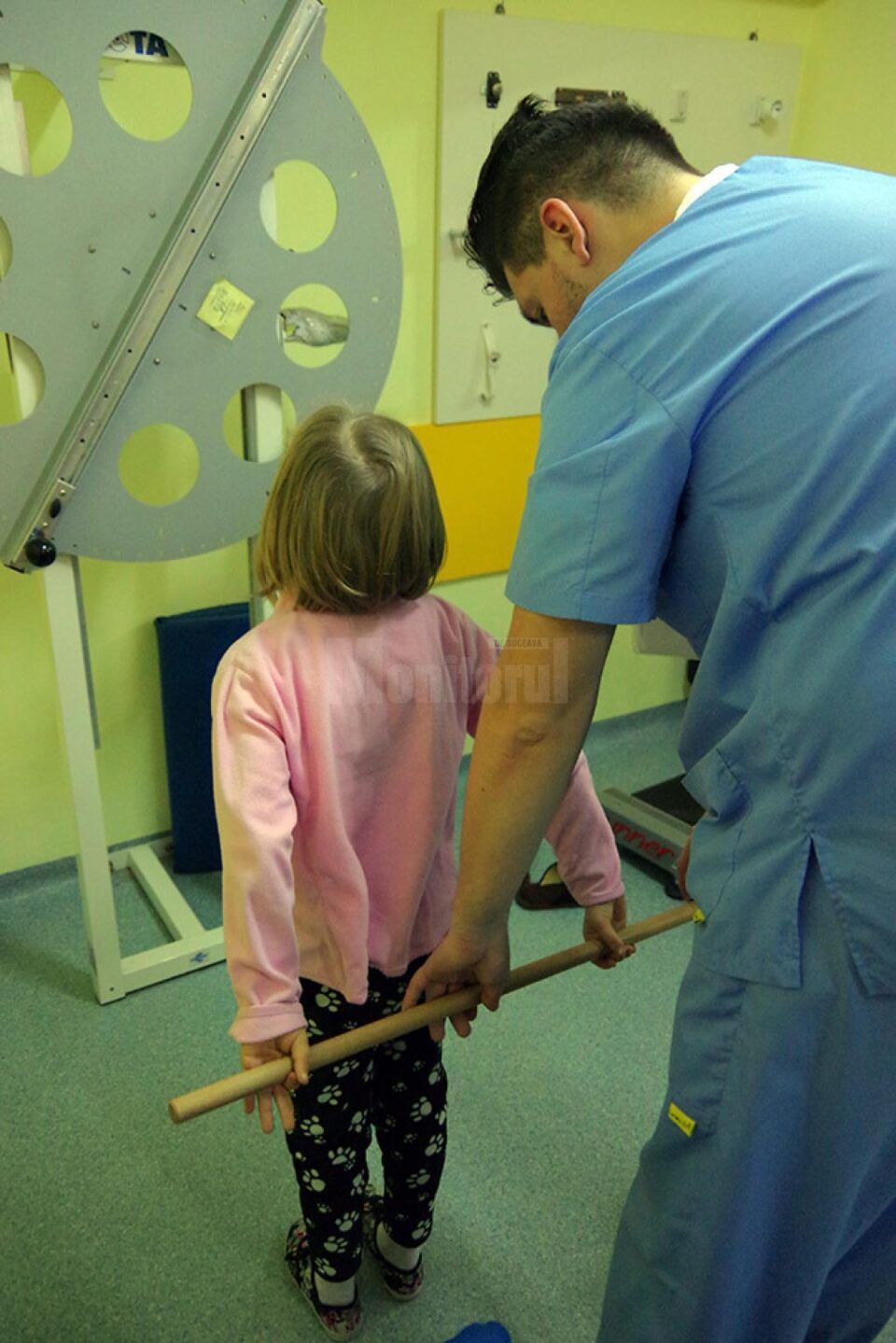 Copilul este îndrumat de specialist pentru a executa corect exercițiile