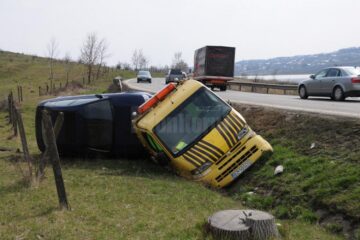 În urma impactului, autoutilitara s-a răsturnat în afara drumului iar autoturismul de pe platformă a fost și el avariat