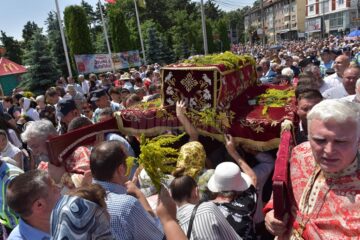 Oamenii arunca flori de sânziene pe raclă