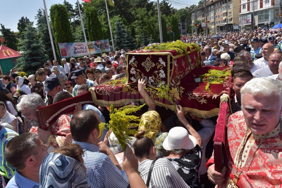 Oamenii arunca flori de sânziene pe raclă
