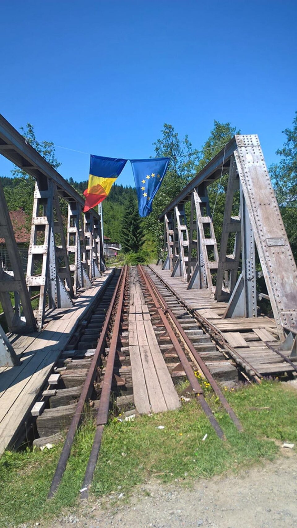 Pe podul metalic aflat chiar în Dornișoara, flutură ironic două steaguri: al României și al Uniunii Europene