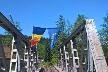 Pe podul metalic aflat chiar în Dornișoara, flutură ironic două steaguri: al României și al Uniunii Europene
