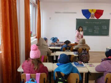 Elevii stau cu căciuli și geci în sălile de curs