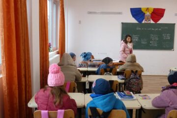Elevii stau cu căciuli și geci în sălile de curs