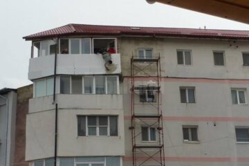 "Batman"-ul Dorel, lucrând la izolarea termică a unui balcon aflat la etajul cinci al clădirii, ținut de haină de un coleg
