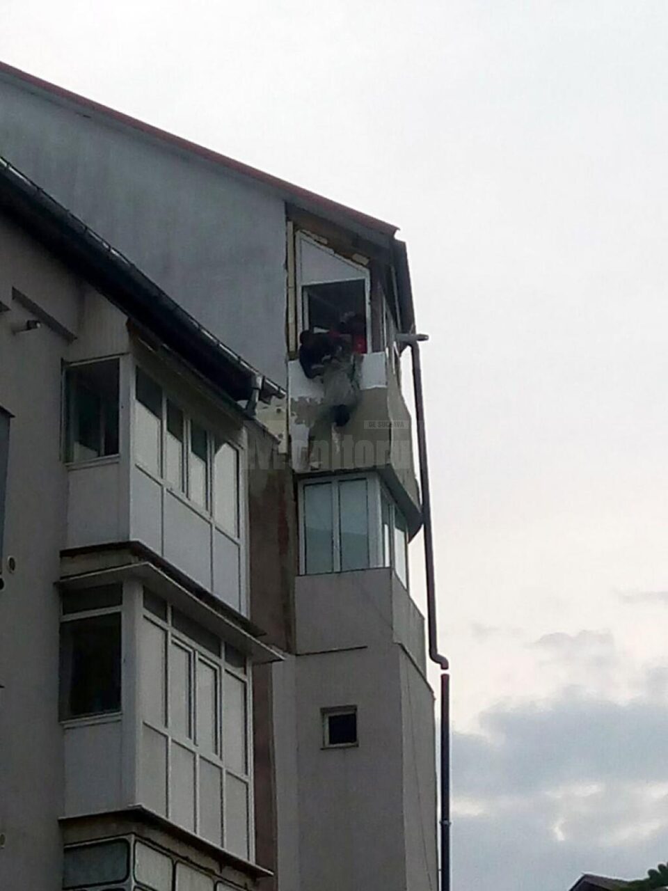 "Batman"-ul Dorel, lucrând la izolarea termică a unui balcon aflat la etajul cinci al clădirii, ținut de haină de un coleg
