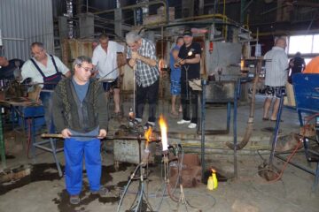 Angajați modelând sticla în jurul cuptorului de lucru la Stil Glass Angajați modelând sticla în jurul cuptorului de lucru la Stil Glass