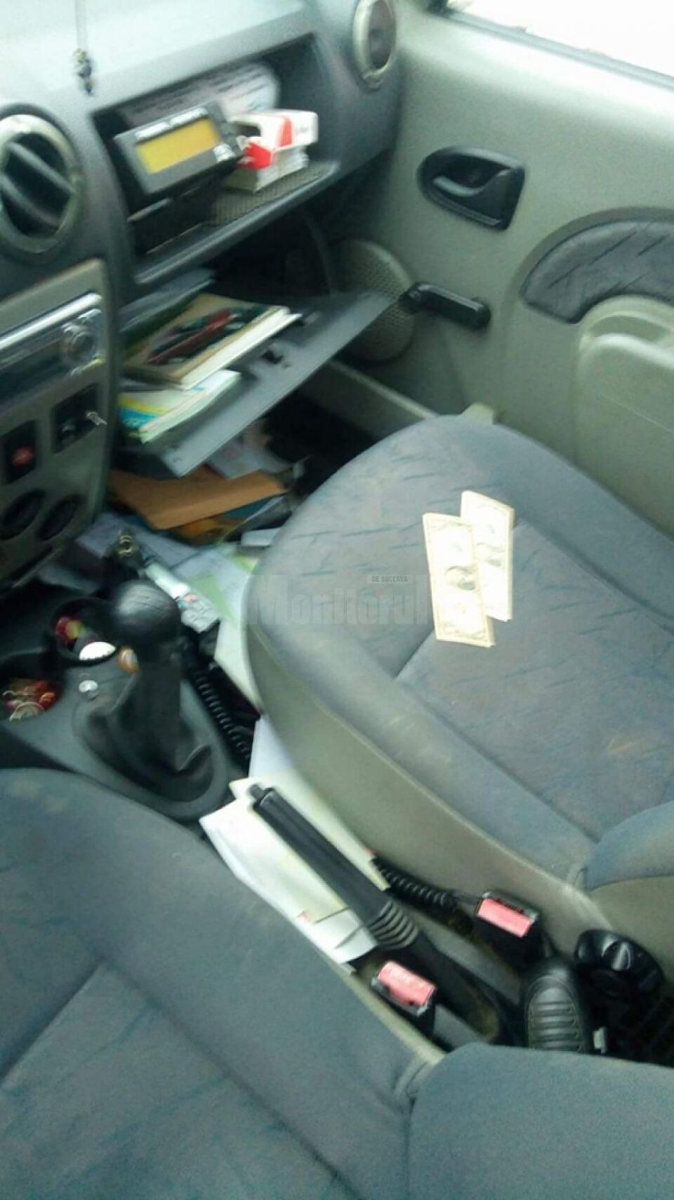 Taximetristul a găsit torpedoul răvășit și cele două bancnote de câte 1 dolar, lăsate de hoț pe scaunul din dreapta față Taximetristul a găsit torpedoul răvășit și cele două bancnote de câte 1 dolar, lăsate de hoț pe scaunul din dreapta față